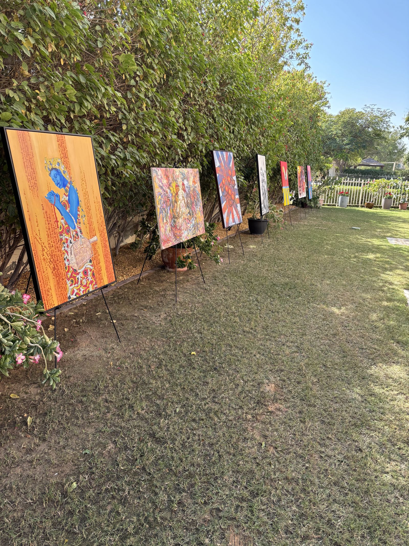 A row of paintings on easels on a lawn